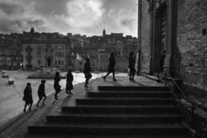 Piazza Armerina (Enna), Chiesa di Santo Stefano, 2018. Alcune parenti si recano alla messa di trigesimo a suffragio del parente defunto: i riti trigesimali, solitamente eseguiti a trenta giorni dalla morte, ricoprono un ruolo centrale nella liturgia funebre cattolica in quanto riti commemorativi e di accompagnamento dell’anima verso l’aldilà.
